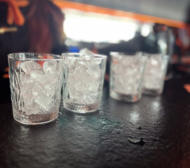Crystal glasses filled with ice cubes resting on bar counter