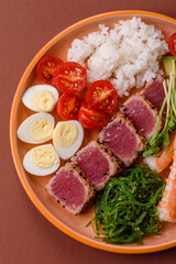Seafood bowl, tuna tataki fillet slices with rice, oranges, tomatoes and sauce. Tuna bowl