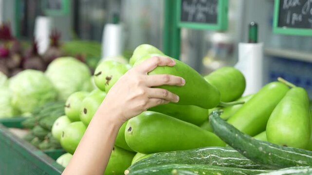 Girl Picking up Bottle gourd on a Street Side Vegetable Store