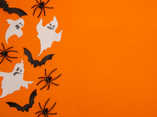  Halloween themed elements, pumpkins, a ghost figurine, bats, spiders and a spider web on an orange...