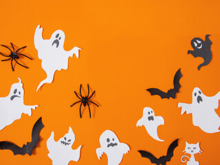  Halloween themed elements, pumpkins, a ghost figurine, bats, spiders and a spider web on an orange...