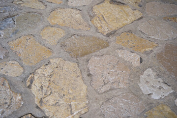Textured stone pavement with irregular shapes and colors creating a rustic outdoor flooring appearance