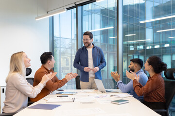A diverse business team engages in a professional meeting, showing appreciation and collaboration.
