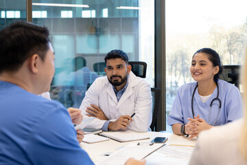 Doctors and nurses engage in a focused discussion during a meeting at their workplace. The professional atmosphere highlights teamwork and communication amidst medical professionals