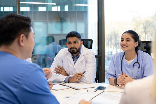 Doctors and nurses engage in a focused discussion during a meeting at their workplace. The professional atmosphere highlights teamwork and communication amidst medical professionals