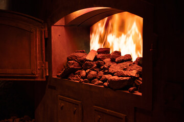 open furnace door in boiler room with flame and pieces of coal, heating with coal, carbon footprint