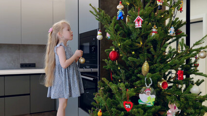 Young girl adorns a modern kitchen with a golden ornament while embracing the holiday spirit of...