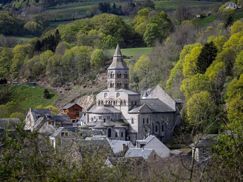 Romanesque Basilica of Orcival nestled in the green hills of Auvergne, France. Historic pilgrimage site and architectural gem in every season.
