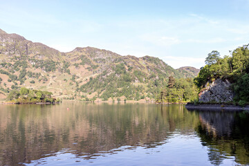 Fototapeta premium View across Loch Katrine, from the north shore road near Trossachs Pier. Loch Lomond and the Trossachs National Park, Southern Highlands of Scotland.