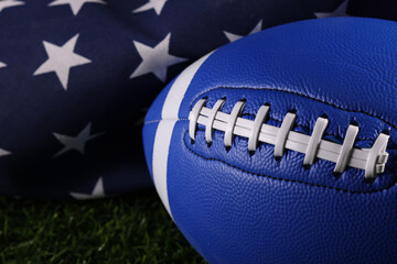 Football on a green field with white stripe and American flag behind