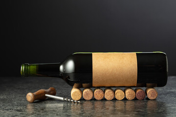 Corkscrew and bottle of wine on a black stone table.