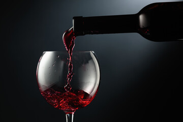 Pouring red wine into a wine glass.