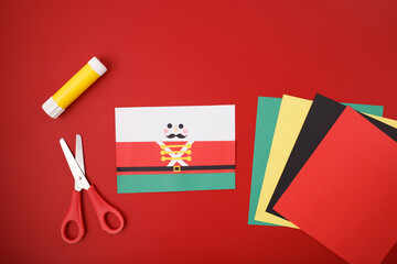 Festive DIY craft scene with scissors, glue stick, cardboard tube, colored paper shapes for nutcracker project, ideal for holiday marketing, kids workshops, craft store promotions, educational