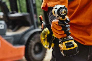 Worker on a construction site, holding a cordless drill with tool belt with building tools on the...