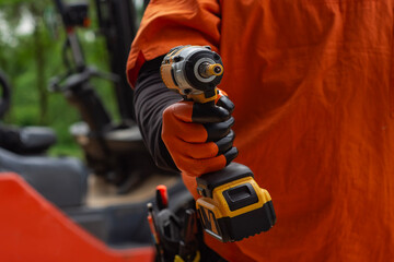 Worker on a construction site, holding a cordless drill with tool belt with building tools on the...