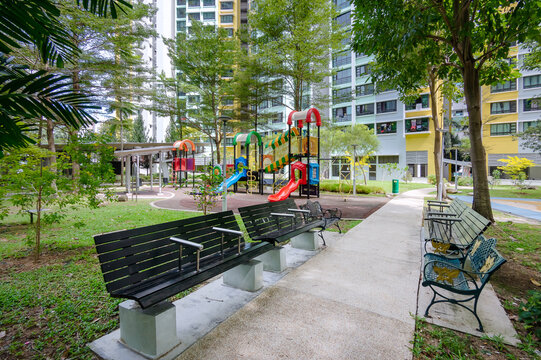 A garden path, rest area, and playground in a green landscape within an HDB estate, Singapore. Shaded by trees, the path and playground invite residents to enjoy a peaceful stroll in the landscape,
