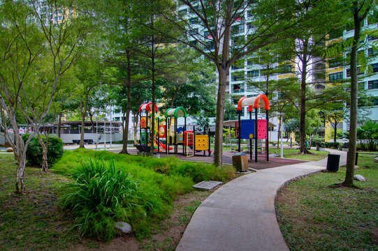 A garden path, rest area, and playground in a green landscape within an HDB estate, Singapore. Shaded by trees, the path and playground invite residents to enjoy a peaceful stroll in the landscape,
