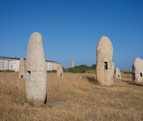 Fields withj contemporary menhirs with the Ancient Roman Tower of Hercules in the background, A...