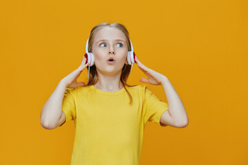 A cheerful girl listening to music with headphones, expressing joy against a bright yellow...