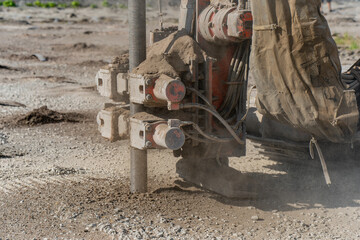 Heavy drilling machine penetrating concrete ground at construction site with dust and vibrations...