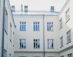 Symmetrical view of white residential courtyard building with classic windows and rooftop details...