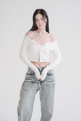 Pretty young fashion sensual woman posing on white wall background dressed in white top and jeans...
