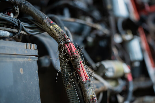Frayed electrical wiring harness with exposed red cables in machinery symbolizing hazard malfunction technical breakdown repair urgency and industrial electrical safety problem