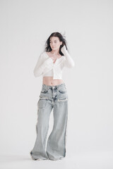 Pretty young fashion sensual woman posing on white wall background dressed in white top and jeans...