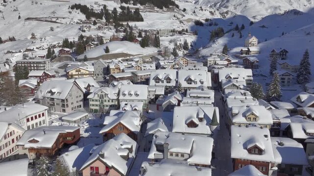 Andermatt, Switzerland in Winter. Aerial of mountain village in Swiss alps in Canton Uri on sunny day after snow fall. 