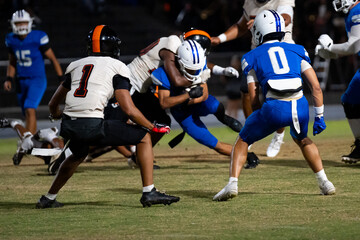 Two players crouch ready as running back charges with fierce determination as defender lunges to stop him mid-play—intensity peaks in this football clash frozen in time.