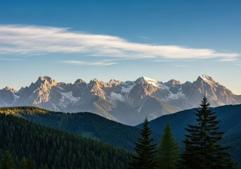 Fototapeta premium Majestic mountain range with snowcapped peaks under a blue sky with wispy clouds at sunset