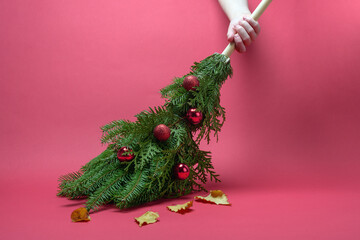 Hand sweeps autumn leaves with a festive evergreen broom adorned with red baubles, signaling cheerful holiday cleanup and fresh start.