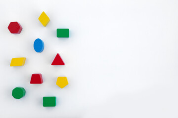 Colorful geometric shapes arranged on white surface for educational play and learning activities,...