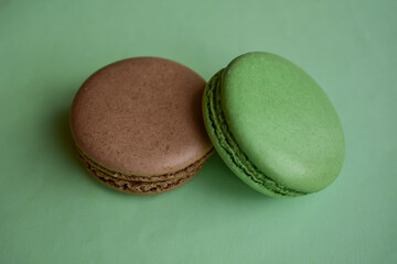 Cake french macaroon  on green background. Sweet and colorful dessert. Two colorful macaroons . Green and brown macaroons.