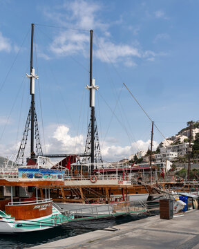 Kusadasi, Turkey - April 3, 2025: Traditional wooden gulets docked in Kusadasi harbor, with hillside buildings and a partly cloudy sky. Scenic coastal view of the Aegean Sea