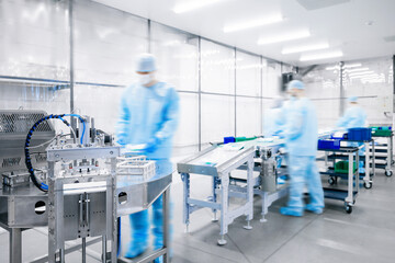 Fototapeta premium Medicine factory, sterile box production line for medical instruments and surgical kits. Workers in uniformed pack scalpels, clamps, tweezers and bandages on conveyor belt