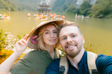 Caucasian couple exploring scenic ninh binh, vietnam: travel adventure on tranquil waters