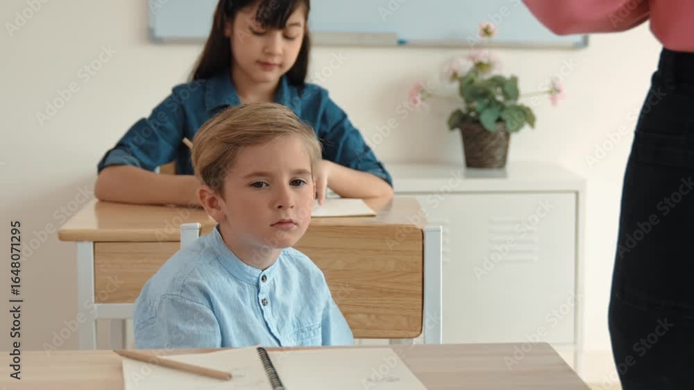 Aufkleber bored elementary student looking at teacher while attend in classroom. diverse smart student sitting