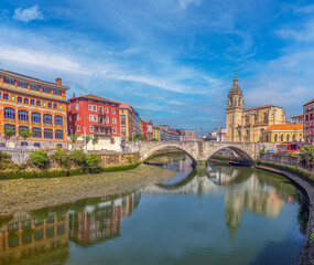 Obraz premium Scenic Nervion River banks along the old city of Bilbao, featuring the historic church of San Antón and the San Antón Bridge, Biscay, Basque Country, northern Spain