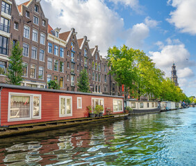 Naviganting along the Prinsengracht canal with the iconic bell tower of the Westerkerk church in the background, Amsterdam, Holland, the Netherlands