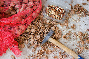 Organic walnuts, shelled walnuts with a hammer, old way of shelling walnuts, pile of walnuts with a shovel and a red bag of nuts