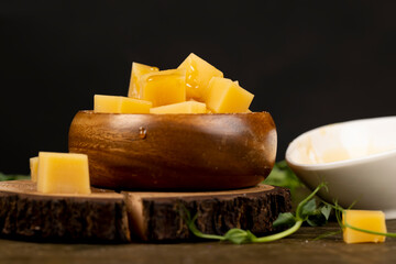 diced in a wooden bowl cheese and honey close up, cheese and sweet bee honey