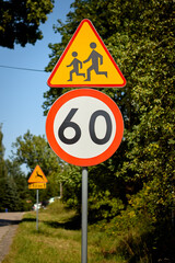 Children crossing warning sign with 60 km speed limit on a sunny day