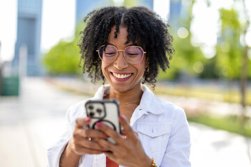Portrait of a smiling young woman using mobile phone in the city
