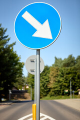 Keep left blue circular road sign on roadside with trees in background