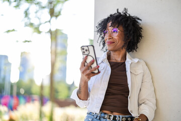 Portrait of a smiling young woman using mobile phone in the city

