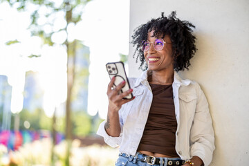 Portrait of a smiling young woman using mobile phone in the city
