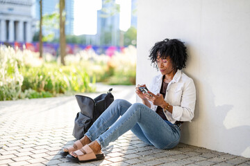 Portrait of a smiling young woman using mobile phone in the city
