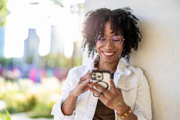 Portrait of a smiling young woman using mobile phone in the city

