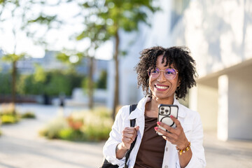 Portrait of a smiling young woman using mobile phone in the city
